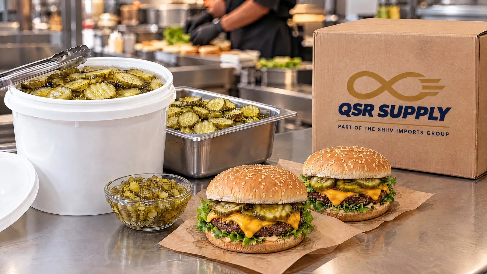 Crinkle cut sliced gherkins in a plain foodservice pail on a stainless QSR prep line beside a bowl of gherkin relish, two burgers on kraft wraps and a kraft carton carrying the QSR Supply logo